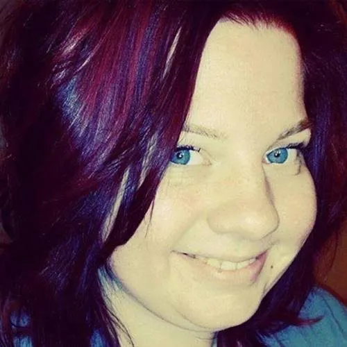 Alicia Hummel smiling, with dark red and purple hair and blue eyes, in a close-up